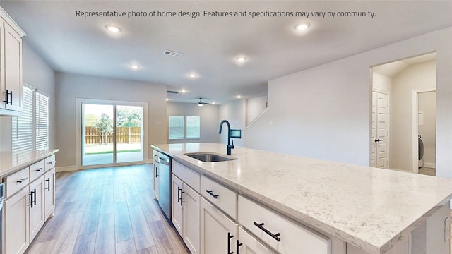 kitchen featuring ceiling fan, light hardwood / wood-style flooring, a center island with sink, sink, and white cabinets