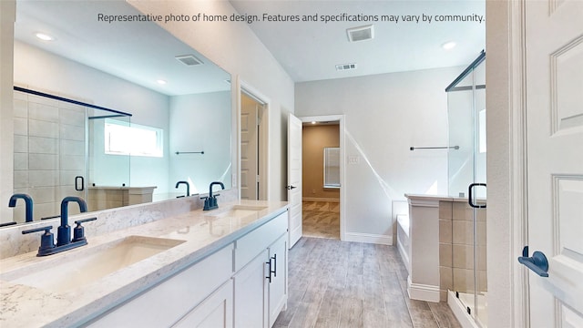 full bathroom featuring shower with separate bathtub, double sink, hardwood / wood-style flooring, and large vanity