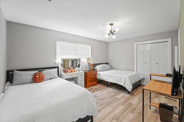 bedroom with a closet, light wood-type flooring, and a chandelier