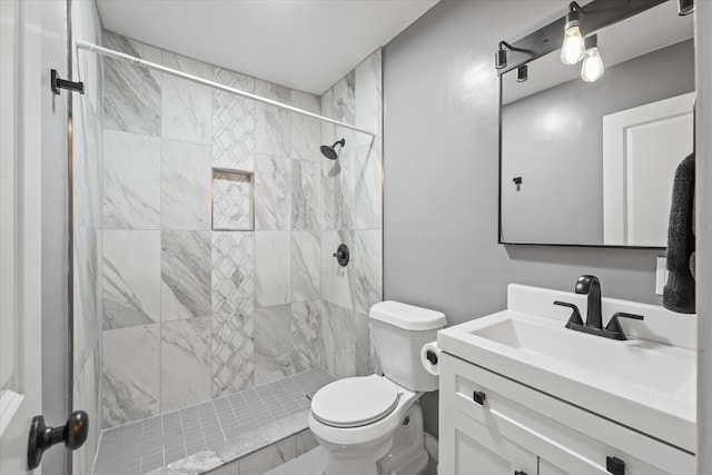 bathroom with tiled shower, vanity, and toilet