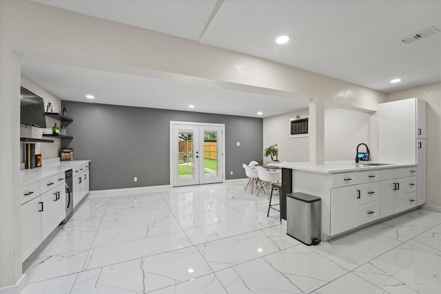 kitchen with kitchen peninsula, light tile floors, white cabinets, sink, and french doors