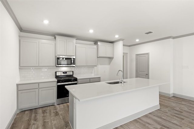 kitchen featuring light hardwood / wood-style floors, sink, appliances with stainless steel finishes, and an island with sink