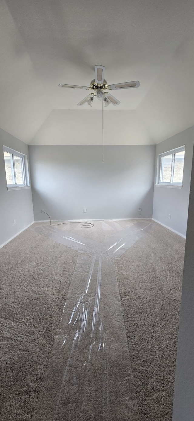 spare room featuring vaulted ceiling, carpet floors, and plenty of natural light