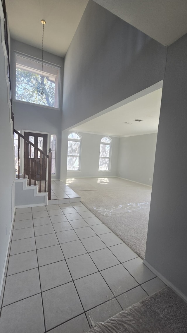 entryway featuring light carpet, plenty of natural light, a high ceiling, and stairway