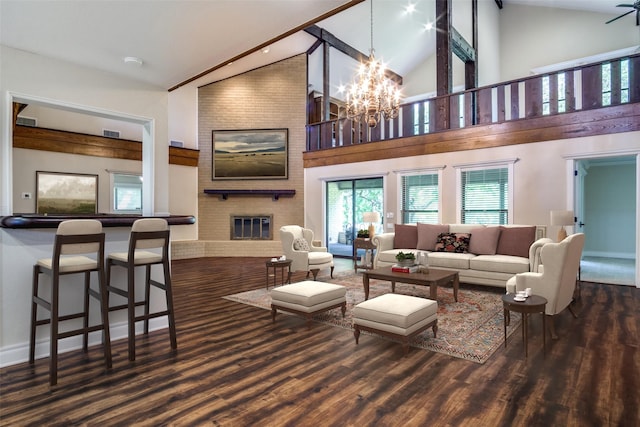 living room featuring a brick fireplace, dark wood-type flooring, high vaulted ceiling, and a chandelier