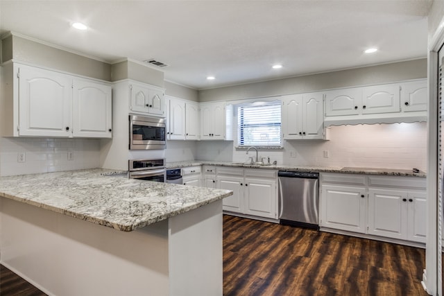 kitchen featuring white cabinets, appliances with stainless steel finishes, kitchen peninsula, and dark hardwood / wood-style floors