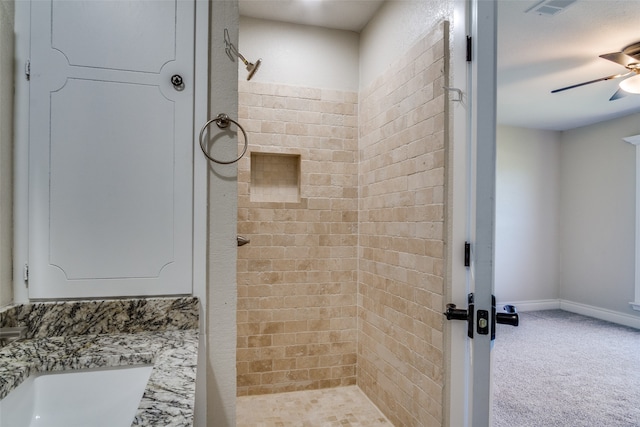 bathroom with vanity, ceiling fan, and tiled shower