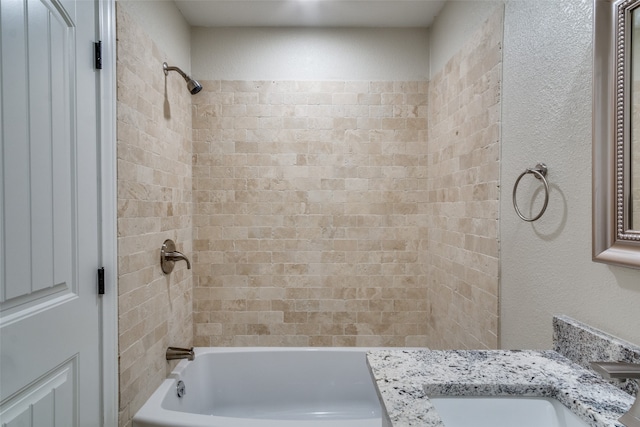 bathroom featuring vanity and tiled shower / bath