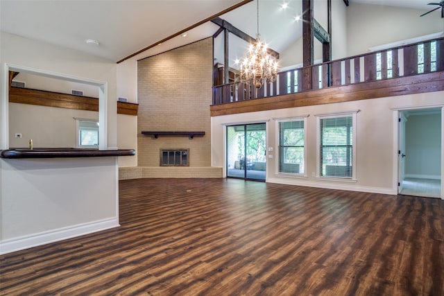 unfurnished living room with high vaulted ceiling, a chandelier, dark hardwood / wood-style floors, and a brick fireplace