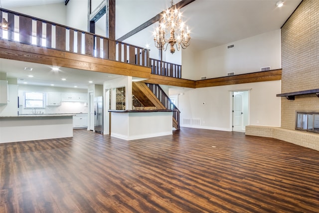 unfurnished living room with a chandelier, a high ceiling, a brick fireplace, and sink