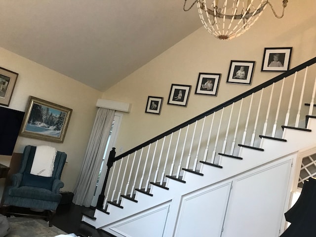 stairway featuring high vaulted ceiling and a notable chandelier