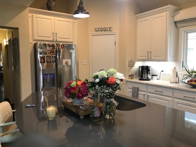 kitchen featuring stainless steel fridge and white cabinetry