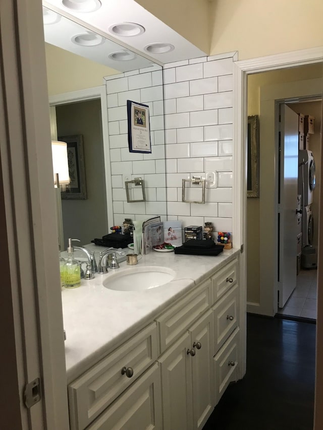 bathroom with vanity, decorative backsplash, and stacked washing maching and dryer