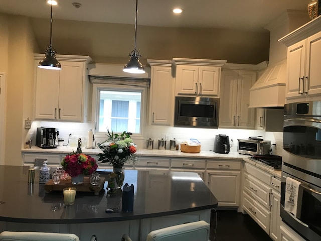 kitchen with decorative backsplash, appliances with stainless steel finishes, decorative light fixtures, and white cabinetry