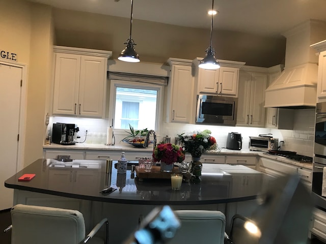 kitchen featuring a kitchen bar, white cabinetry, hanging light fixtures, and stainless steel appliances