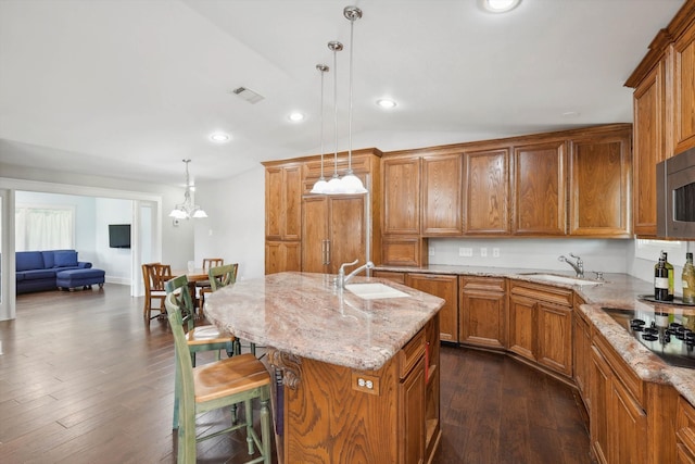 kitchen featuring a center island with sink, dark wood-type flooring, pendant lighting, black electric stovetop, and sink