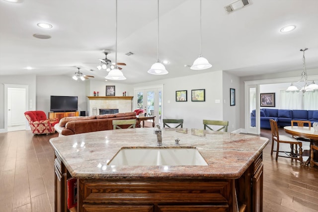 kitchen featuring pendant lighting, a kitchen island with sink, and wood-type flooring