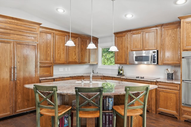 kitchen featuring appliances with stainless steel finishes, hanging light fixtures, a kitchen bar, and an island with sink