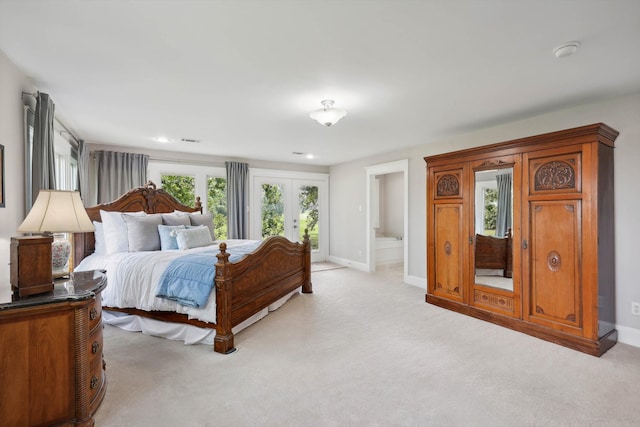 carpeted bedroom featuring multiple windows, french doors, and connected bathroom