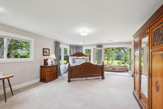 bedroom with light carpet, multiple windows, and access to outside