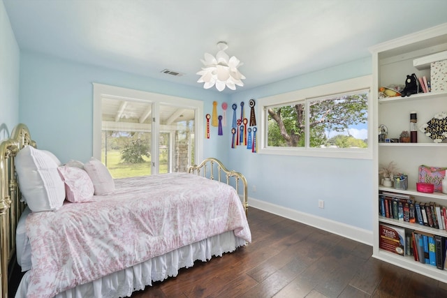 bedroom featuring an inviting chandelier, multiple windows, and dark hardwood / wood-style flooring