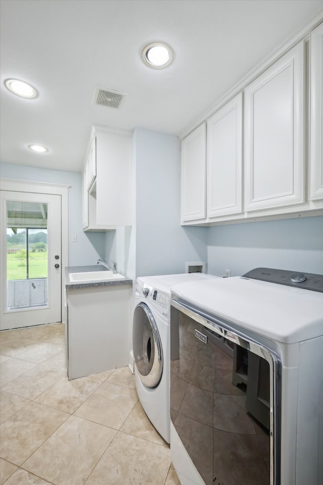 clothes washing area featuring cabinets, sink, washer and clothes dryer, and light tile patterned floors