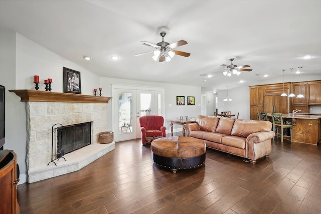 living room featuring dark wood-type flooring, a stone fireplace, and ceiling fan