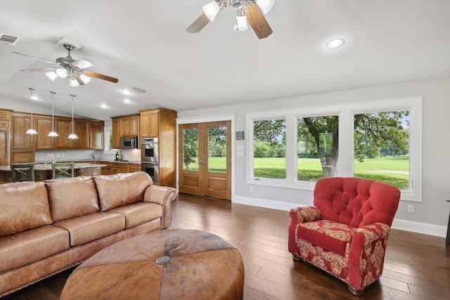 living room featuring ceiling fan, a wealth of natural light, and dark hardwood / wood-style flooring