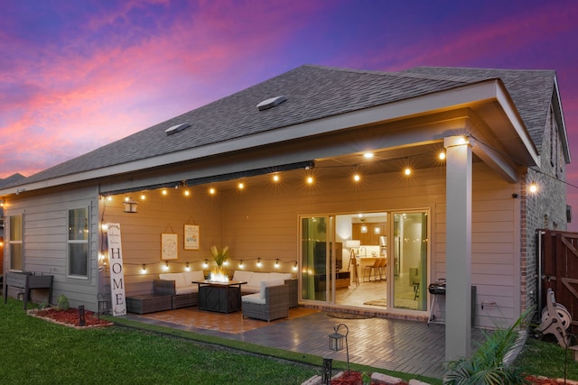 back house at dusk featuring a yard, an outdoor living space with a fire pit, and a patio