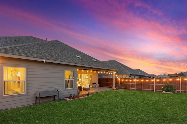 back house at dusk with a patio area and a yard