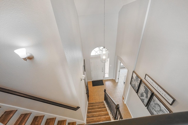 tiled foyer featuring a towering ceiling and a chandelier