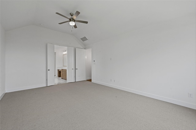 unfurnished bedroom with carpet flooring, ensuite bath, ceiling fan, and vaulted ceiling