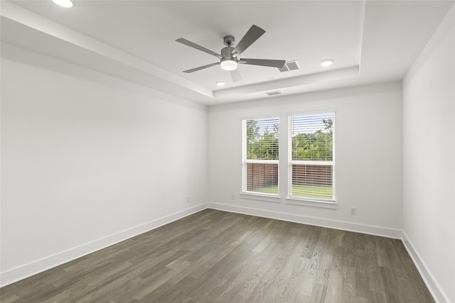 empty room featuring a tray ceiling, dark hardwood / wood-style flooring, and ceiling fan