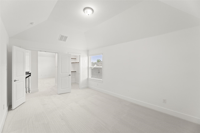 unfurnished bedroom with lofted ceiling, a closet, and light colored carpet