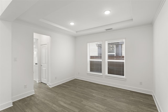 spare room with dark wood-type flooring, a raised ceiling, and ornamental molding