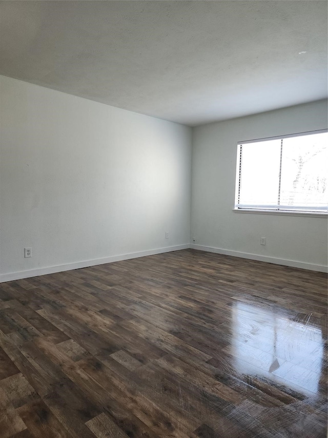 unfurnished room with dark wood-type flooring