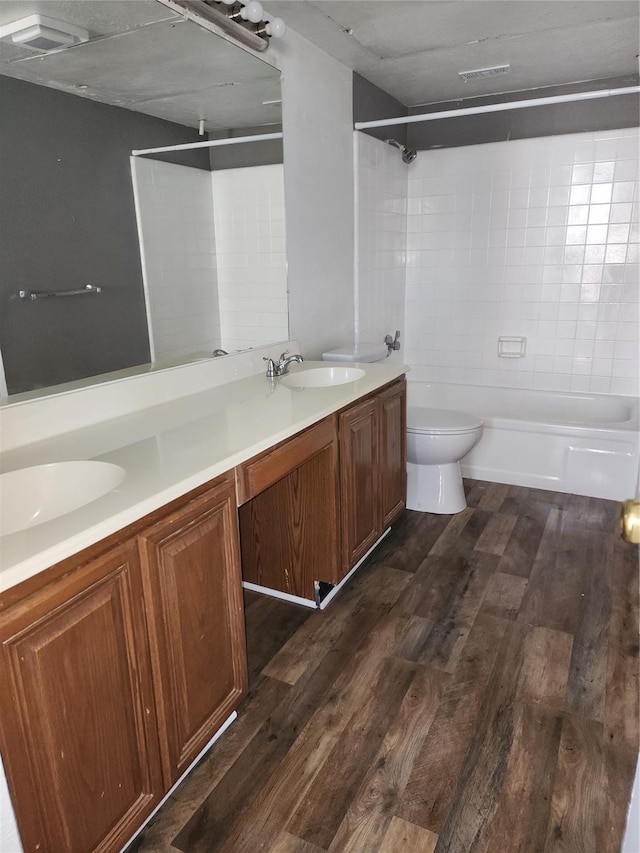 full bathroom featuring tiled shower / bath, hardwood / wood-style floors, double vanity, and toilet