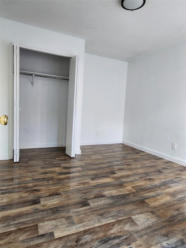 unfurnished bedroom featuring a closet and dark wood-type flooring