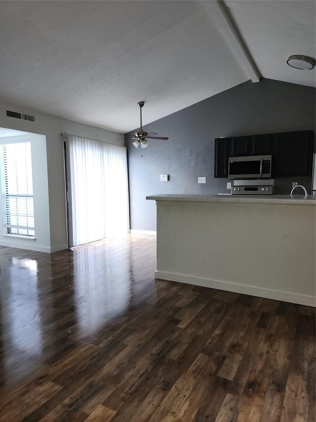 unfurnished living room with vaulted ceiling with beams, ceiling fan, and dark hardwood / wood-style floors