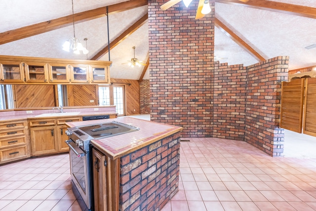 kitchen featuring ceiling fan, stainless steel range, tile counters, beam ceiling, and light tile floors