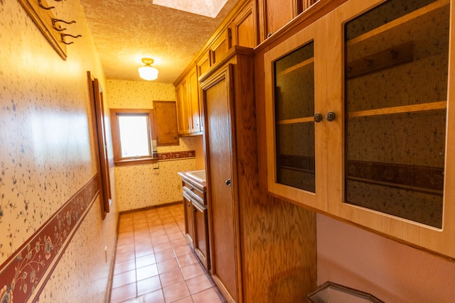 corridor with light tile floors and a textured ceiling