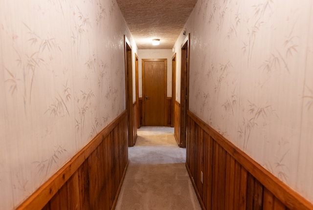 hallway with light colored carpet and a textured ceiling