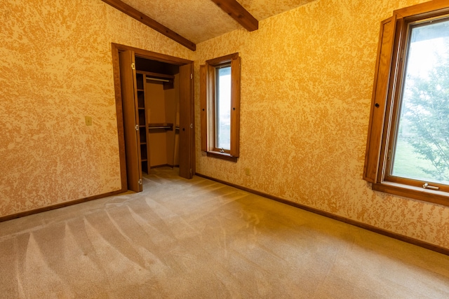 carpeted spare room featuring vaulted ceiling with beams