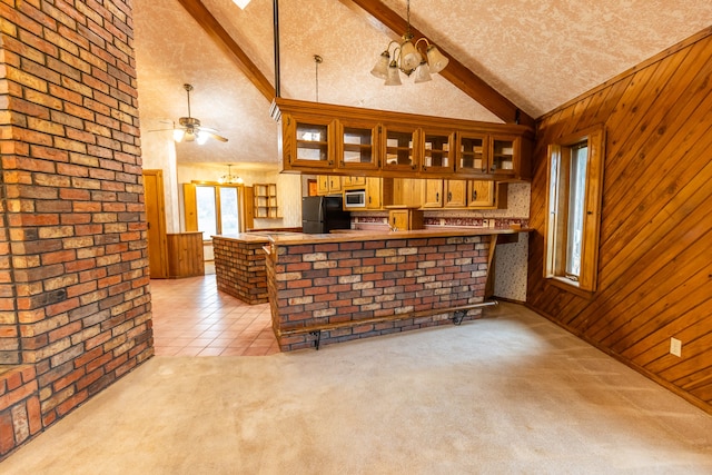 kitchen featuring ceiling fan, kitchen peninsula, black fridge, lofted ceiling with beams, and light colored carpet