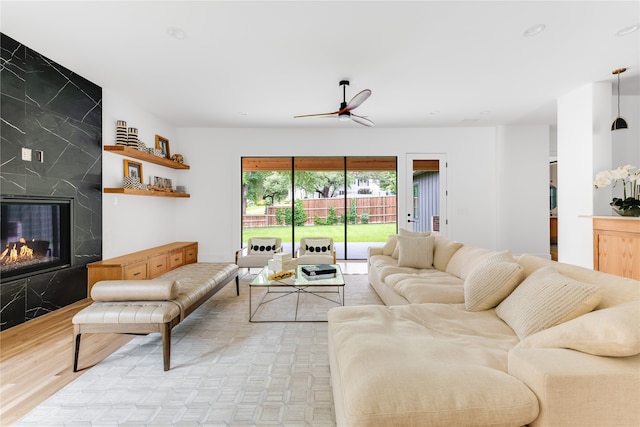 living room with ceiling fan, light hardwood / wood-style flooring, and a high end fireplace