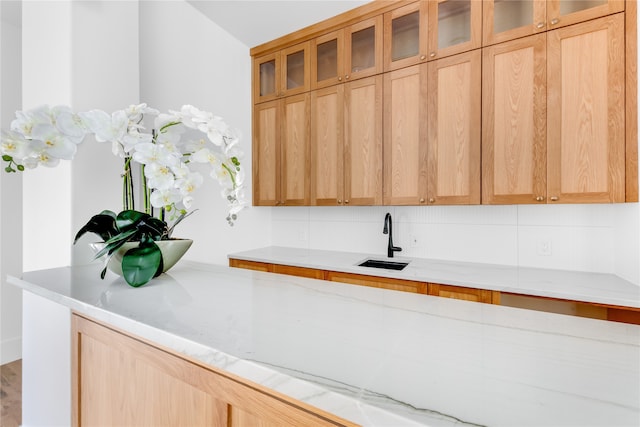 kitchen featuring sink, light brown cabinets, light stone counters, and backsplash