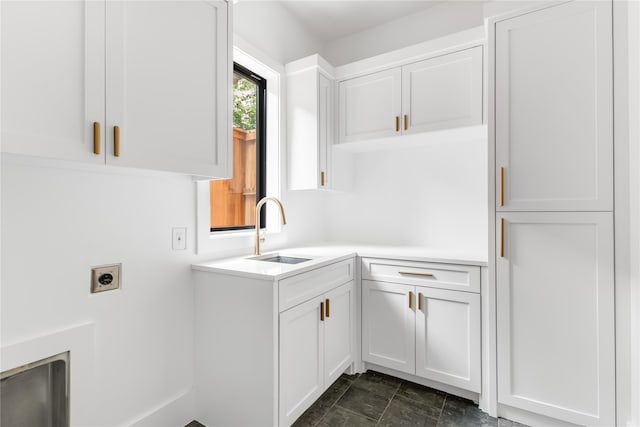 laundry room with electric dryer hookup, cabinets, and sink