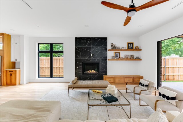 kitchen with stainless steel fridge, white cabinets, a kitchen island with sink, light hardwood / wood-style flooring, and sink