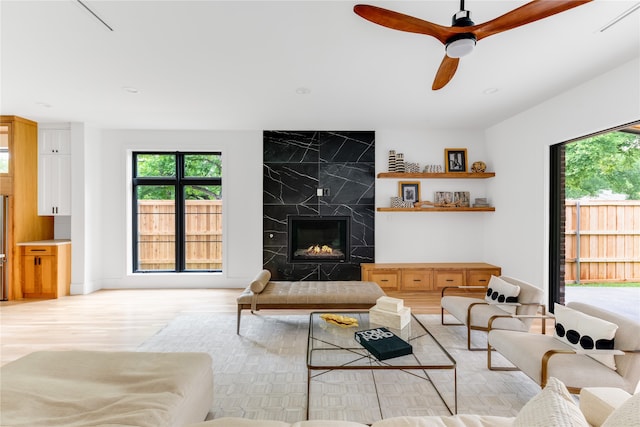 living room featuring ceiling fan, light wood-type flooring, and a fireplace