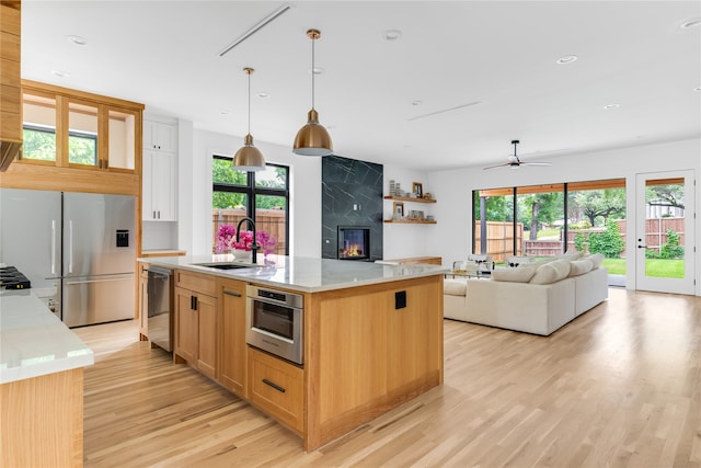 kitchen with a large fireplace, pendant lighting, a healthy amount of sunlight, and ceiling fan